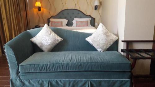 a blue couch in a room with a bed at The Belagri Hotel and Convention in Sorong