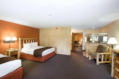 a hotel room with two beds and a chair at AmericInn by Wyndham Pequot Lakes in Pequot Lakes