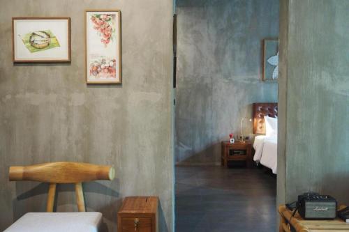 a room with a bedroom with a bed and a chair at The Buffalo Amphawa in Samut Songkhram