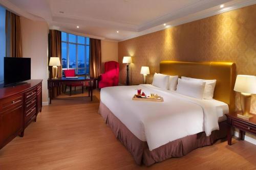 a hotel room with a large bed and a television at Adimulia Hotel Medan in Medan