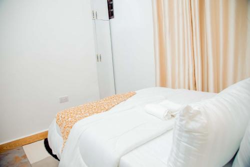 a bed with white sheets and pillows in a room at Stand-alone- 2BR house in Dodoma in Dodoma