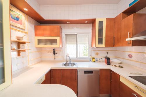 a kitchen with wooden cabinets and a sink at Expoholidys- Chalet privado en Castell del Rey in Almería