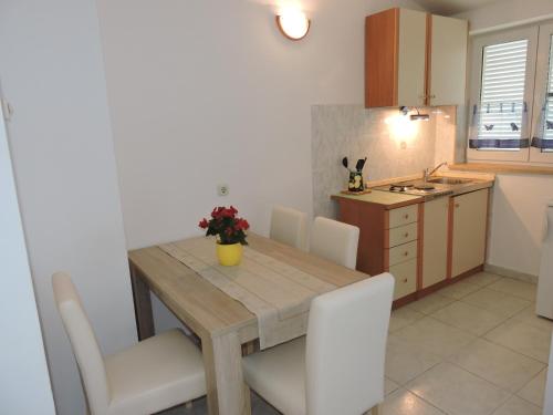 cocina y comedor con mesa de madera y sillas en Apartments Vera, en Ližnjan