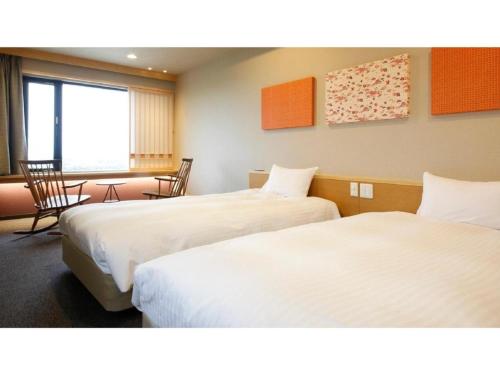 a hotel room with two beds and a table and chairs at Ako Park Hotel in Ako