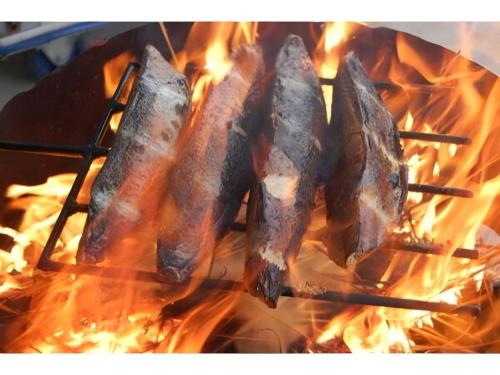 a group of sausages cooking on a grill with flames at AKISAWA HOTEL in Shimanto