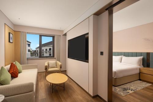 a hotel room with a bed and a couch at Hilton Garden Inn Shaoxing Yuecheng in Shaoxing