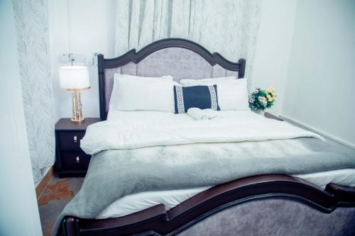 a bedroom with a bed with white sheets and a lamp at Stand-alone- 2BR house in Dodoma in Dodoma