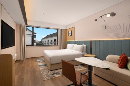 a hotel room with a bed and a couch at Hilton Garden Inn Shaoxing Yuecheng in Shaoxing