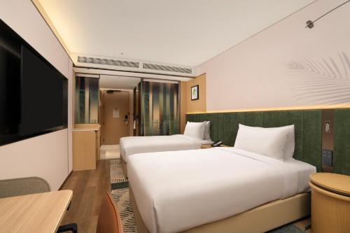 a hotel room with two beds and a flat screen tv at Hilton Garden Inn Shaoxing Yuecheng in Shaoxing