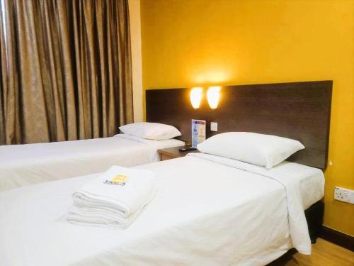 two beds in a hotel room with white sheets at YMCA Kuala Lumpur in Kuala Lumpur