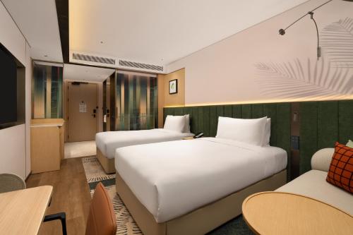 a hotel room with two beds and a couch at Hilton Garden Inn Shaoxing Yuecheng in Shaoxing