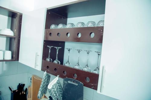 a shelf with wine glasses in a kitchen at Stand-alone- 2BR house in Dodoma in Dodoma
