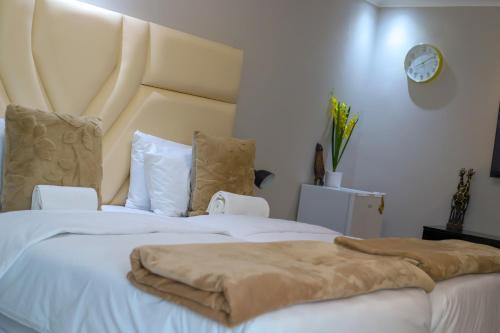a bedroom with two white beds with a large headboard at ECO-WILD Luxury Suites in Windhoek