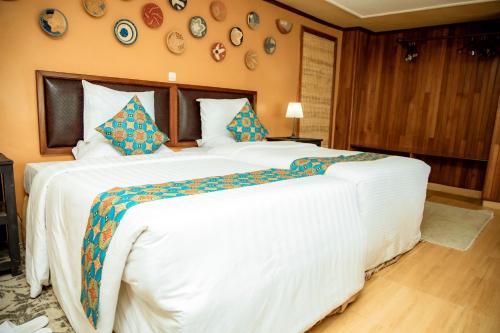 a large white bed in a bedroom with plates on the wall at Mountain Gorilla View Lodge in Ruhengeri