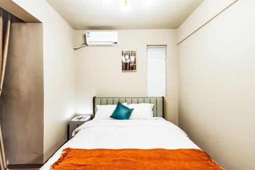 a small bedroom with a bed with an orange blanket at Baihong Riverview Apartment-Hongya Cave in Chongqing