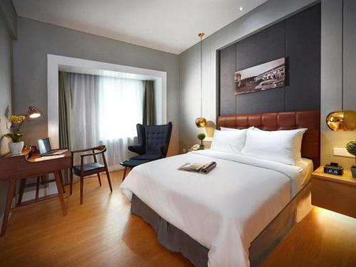 a hotel room with a large bed and a desk at Kingwood Boutique Hotel in Miri