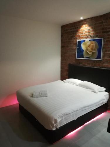 a bedroom with a white bed with a flower on the wall at Rock & Roll Hotel Klang in Klang