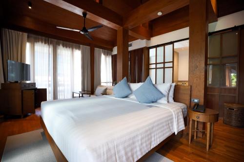 a bedroom with a large white bed with blue pillows at Chann Bangkok Noi in Bangkok