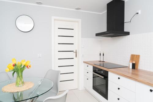 cocina con mesa de cristal y armarios blancos en AnJa Apartment, en Sandomierz