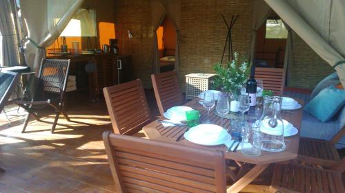 a wooden table with plates and glasses on a patio at Losinj Glamping - Camp Čikat - Wild in Mali Lošinj