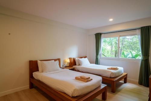 twee bedden in een kamer met een raam bij Mata Pavilion in Loei