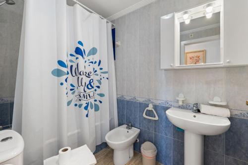 ein Badezimmer mit einem WC-Waschbecken und einem Duschvorhang in der Unterkunft HE Altos de Campoamor in Orihuela