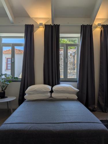 a bed with two pillows in front of a window at Castelo River View - NEW in Vila Nova de Gaia