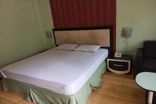 a bedroom with a bed and a chair and a phone at Hotel O Penginapan Al-asharNearWarung Acil Ubai in Purbolinggo