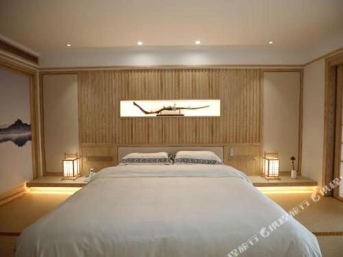 a bedroom with a large white bed with two pillows at Kunming Dianchi Garden Hotel & Spa in Kunming