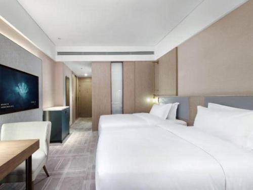 a hotel room with a large white bed and a desk at Empark Grand Hotel Fuzhou in Fuzhou