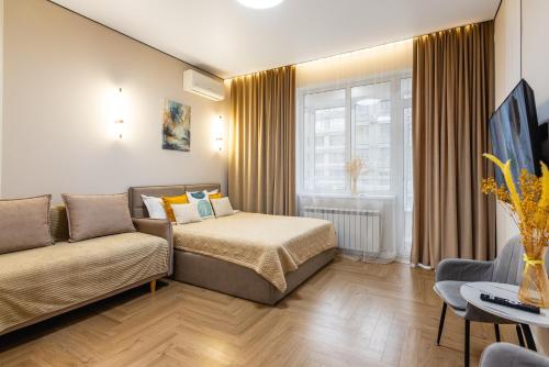 a hotel room with a bed and a couch at Светлая квартира-студия в 5-минутах от Мега Парк in Almaty