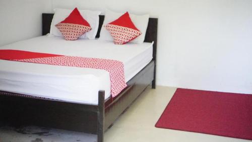 a bedroom with a bed with red and white pillows at OYO 93784 Kost Bu Eli Syariah in Malang