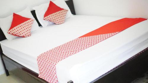 a white bed with red and white pillows on it at OYO 93784 Kost Bu Eli Syariah in Malang