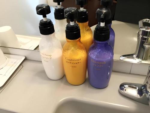 a group of four bottles sitting on a counter next to a sink at Hotel Gran View Okinawa in Naha