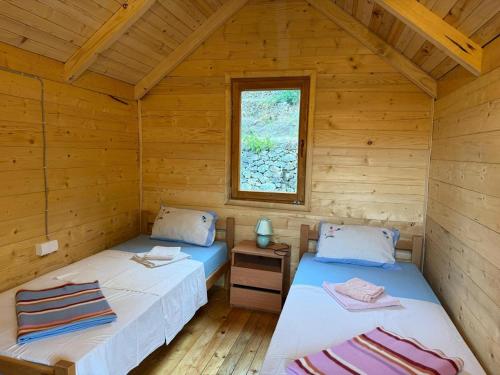 two beds in a log cabin with a window at ORAHOVSTICA TRAIL - Glamping in Dupilo