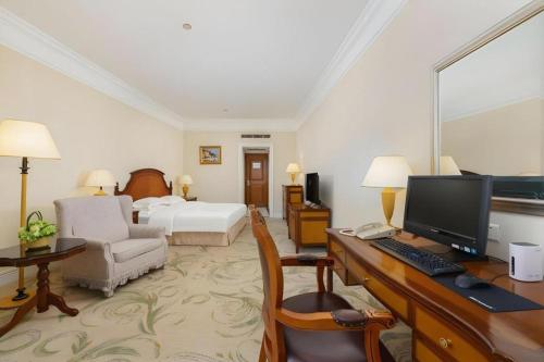 a hotel room with a desk with a computer and a bed at Shantou Golden Gulf Hotel in Shantou