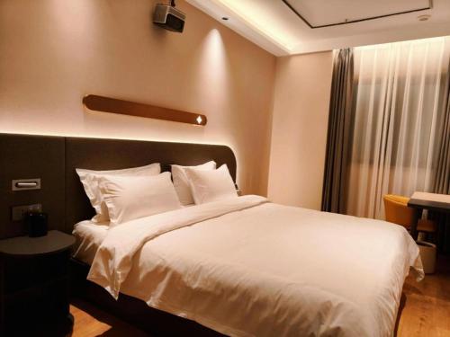 a bedroom with a bed with white sheets and a window at GreenTree Inn Datong YundinGYAyuan Express Hotel in Datong
