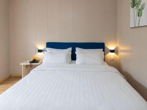 a large white bed in a room with two lamps at 7 Days Inn Changzhou Yancheng Technology Metro Station in Changzhou