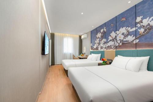大連市にあるJinjiang Inn Dalian North Railway Stationのベッドが2つあり、壁に絵が飾られたホテルの部屋