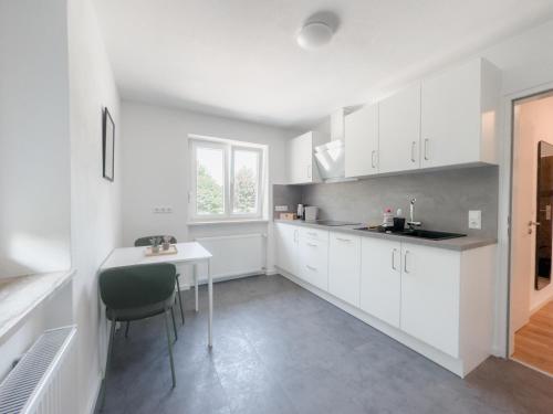 a kitchen with white cabinets and a table and a window at Skyrise Apartments - Zentral mit Küche, Balkon und Parkplatz in Bad Wörishofen
