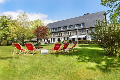 a group of chairs sitting in the grass in front of a building at Berghotel Hoher Knochen - Ruhe & Natur in Winterberg