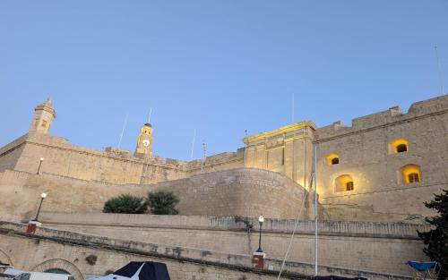 a large stone building with a clock tower on it at Cottonera Lines Boutique Holiday Accomodation in Cospicua