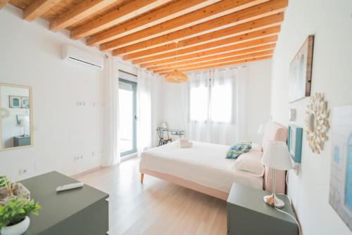 a white bedroom with a large bed and wooden ceilings at Apartamentos San Francisco con Terraza privada by Expoholidays in Almería