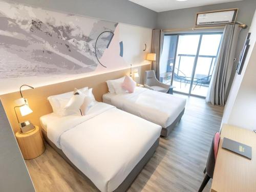 a hotel room with two beds and a window at Imin Hotel in Huadu