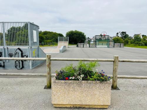 a fence with a potted plant in front of a skate park at L'Echappée familiale en bord de mer in Plozévet