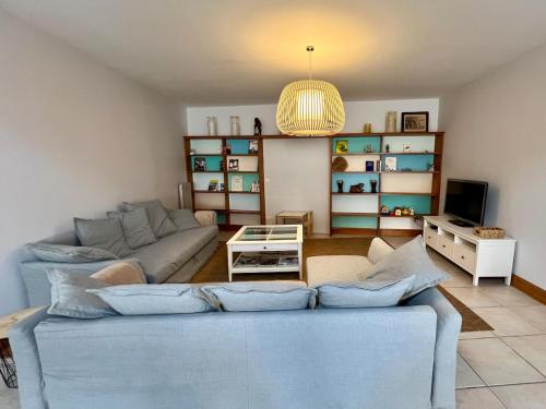 a living room with a blue couch and a tv at L'Echappée familiale en bord de mer in Plozévet
