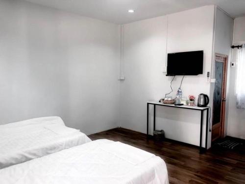 a white room with two beds and a flat screen tv at Capital O 75412 V Resort in Ban Wang Ton
