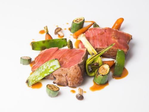 a piece of meat with vegetables on a white plate at The Cookbook Gastro Boutique Hotel & SPA in Calpe