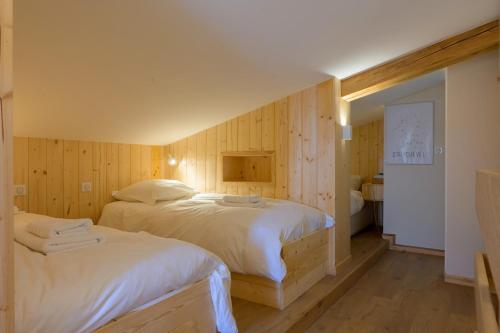 a bedroom with wooden walls and a bed with white sheets at Refuge Mil100 Chalet-spa Luxe 5 in Metzeral
