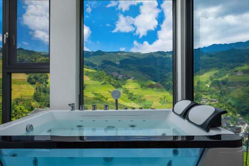 a bath tub in a room with a large window at Enjoy the panoramic view of the rice fields (Longsheng Longji Terraces Branch) in Heping